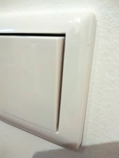 Close-up of a white light switch on a light-colored wall