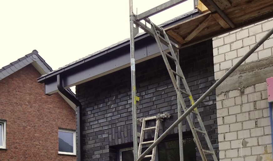 Exterior view of a construction site with scaffolding in front of dark masonry