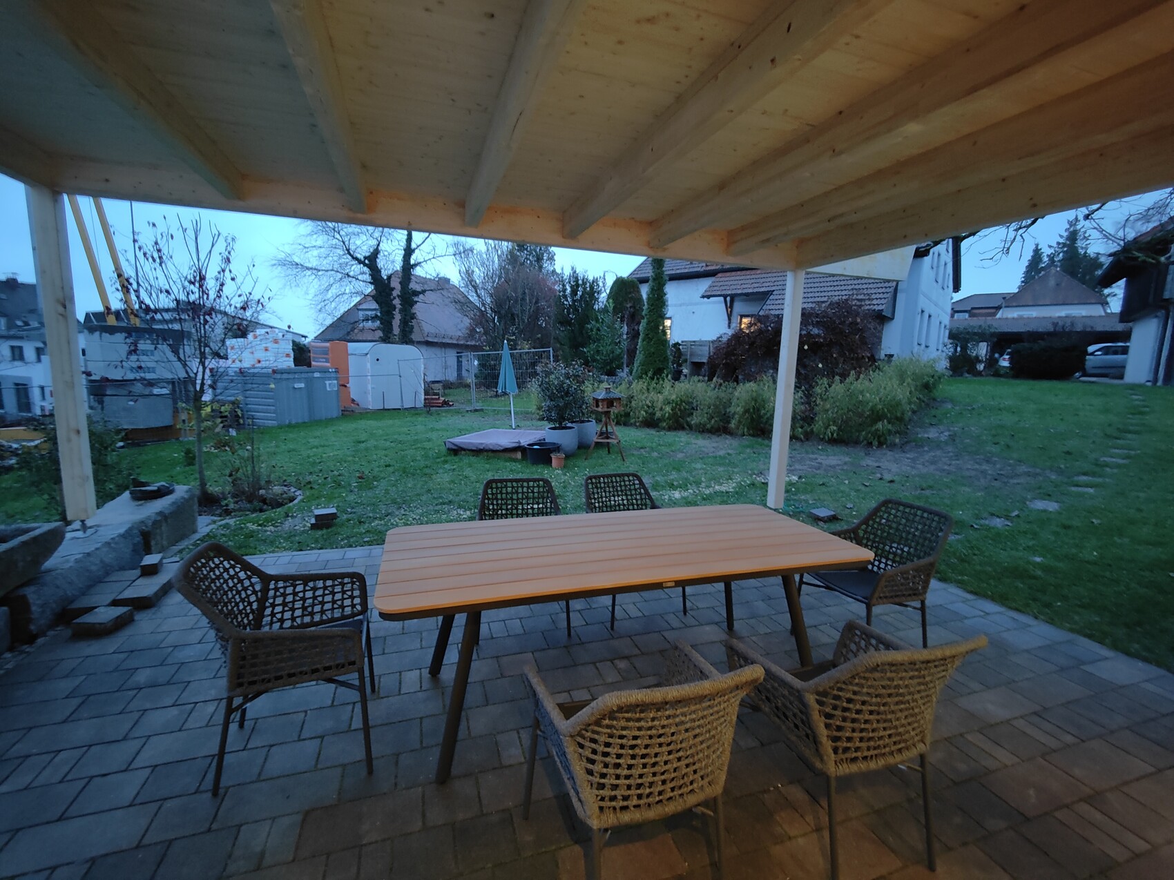 Covered terrace with rectangular wooden table and six rattan chairs in the garden