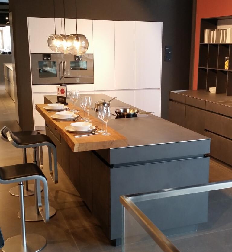 Modern kitchen with island, white cabinets and bar stools in showroom.
