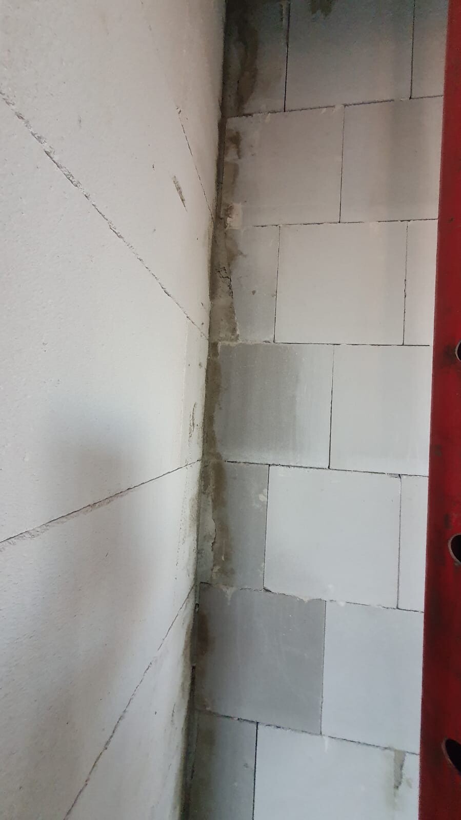 Interior wall corner: left white wall, right gray tiles, red border on the right