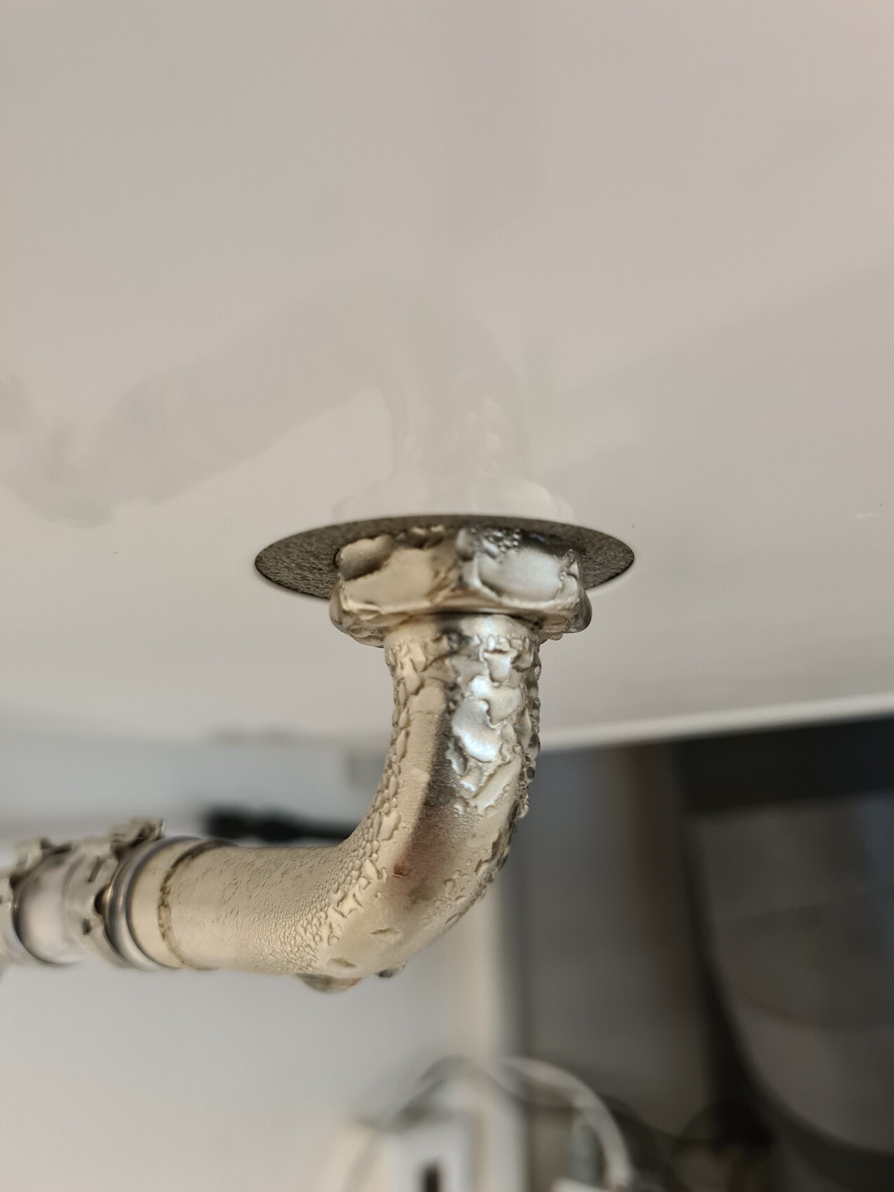 Rusty pipe with white lime deposits under the sink.