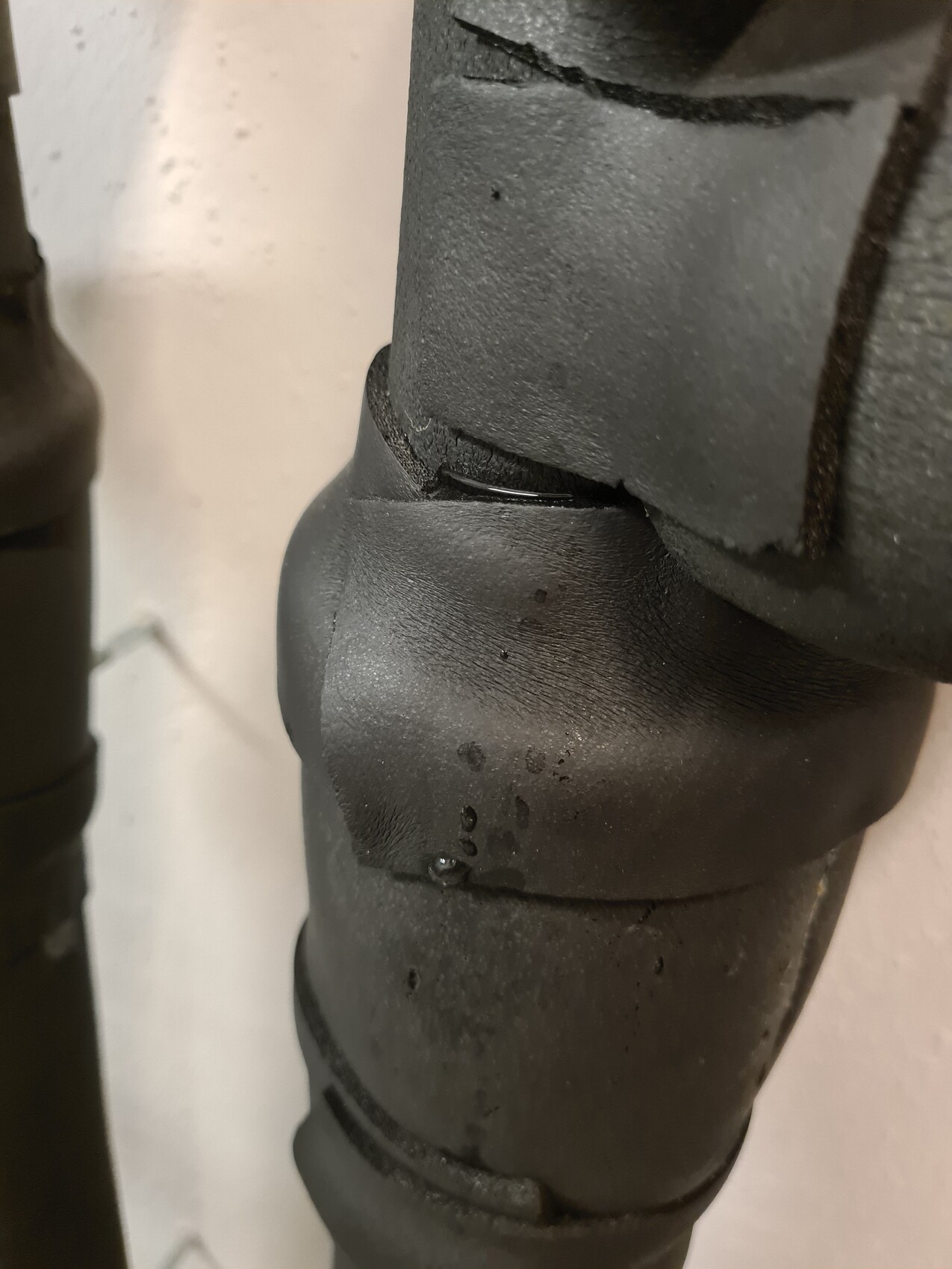 Close-up of a black pipe connector with a crack in the seal.
