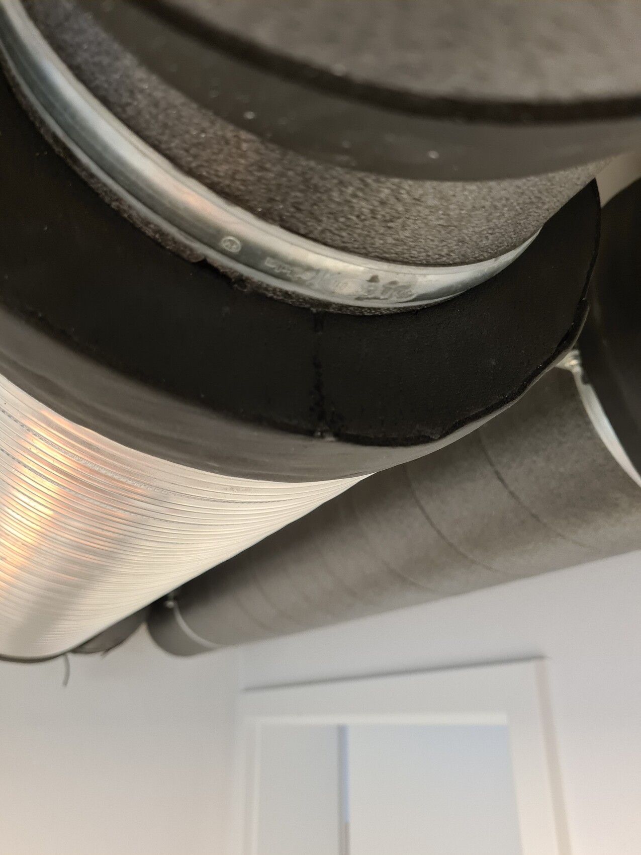 Close-up of a round metal duct with seal and insulation.