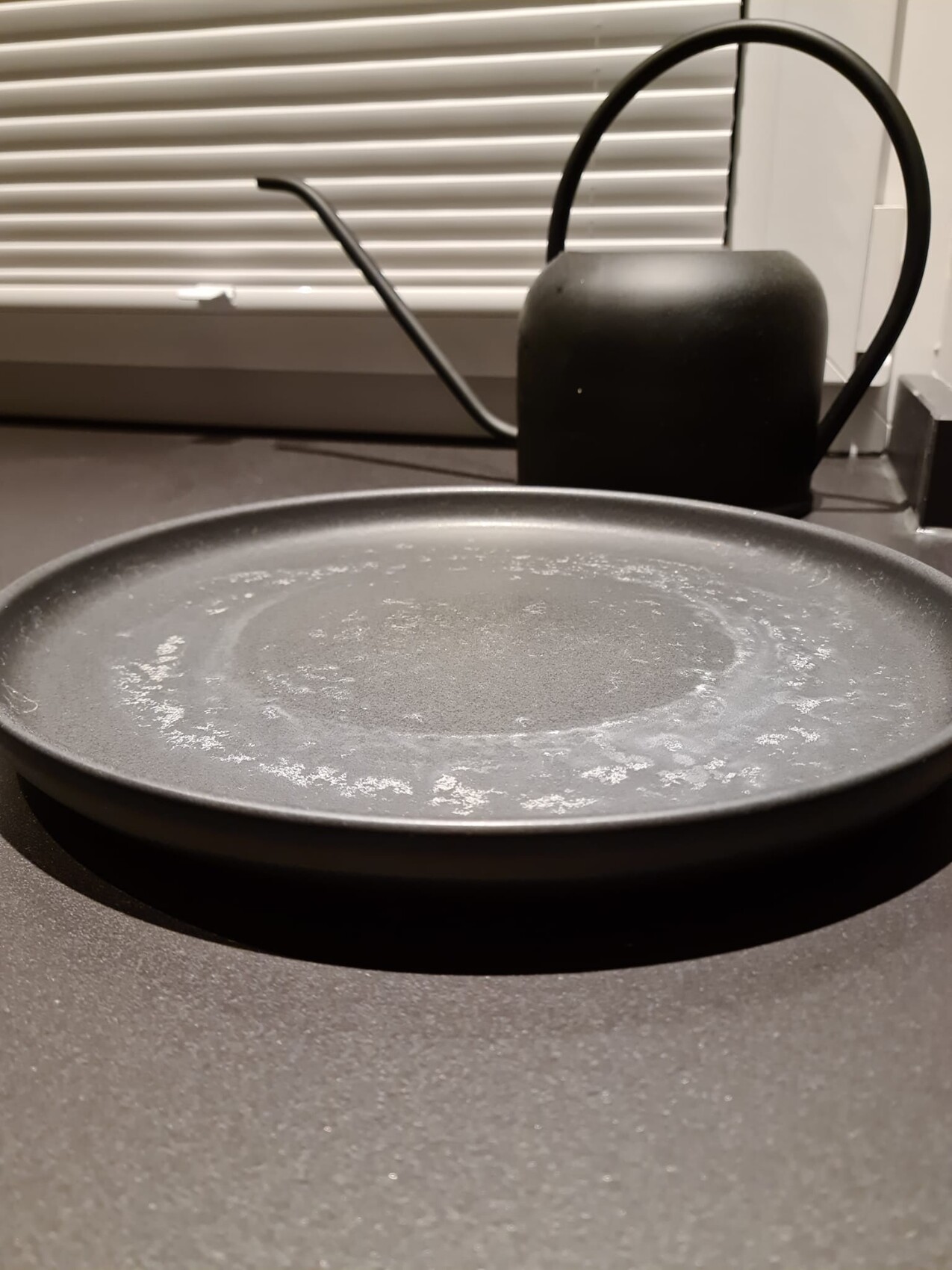 Black pan lying on the stove in a kitchen scene, kettle in the background