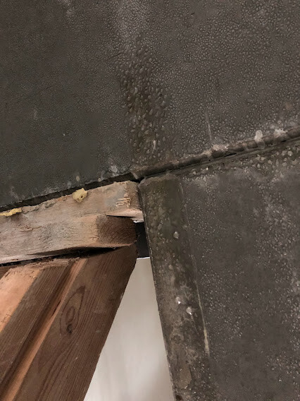 Close-up of a wooden beam next to a concrete surface with an open gap between wood and concrete.