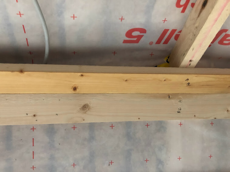 Construction wooden beams over plastic foil with red plus signs in a building site scene.