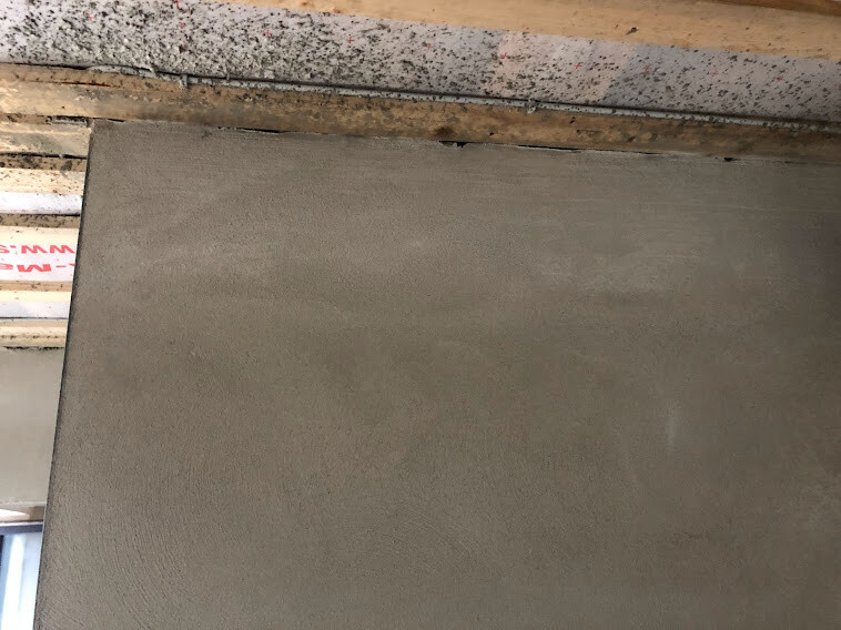 Gray plastered wall surface under rough wooden beam ceiling – construction site character.