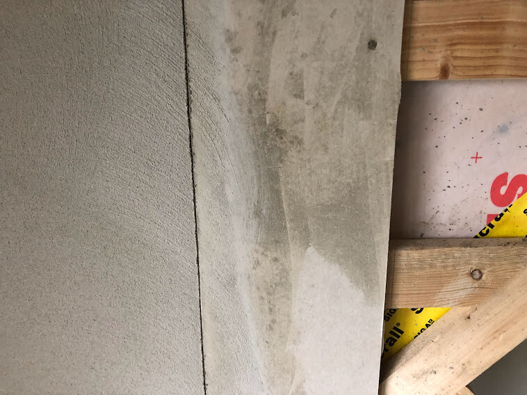 Close-up of a concrete wall next to timber frame construction with yellow safety tape.