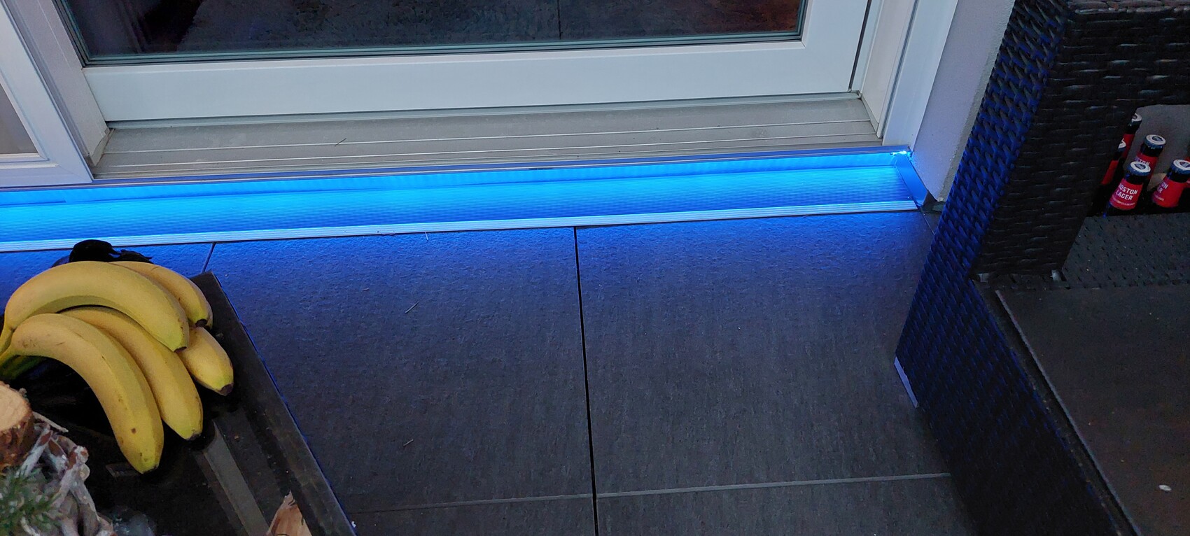 Bananas on the left, blue LED light strip on the door threshold, basket chair on the right and red cans