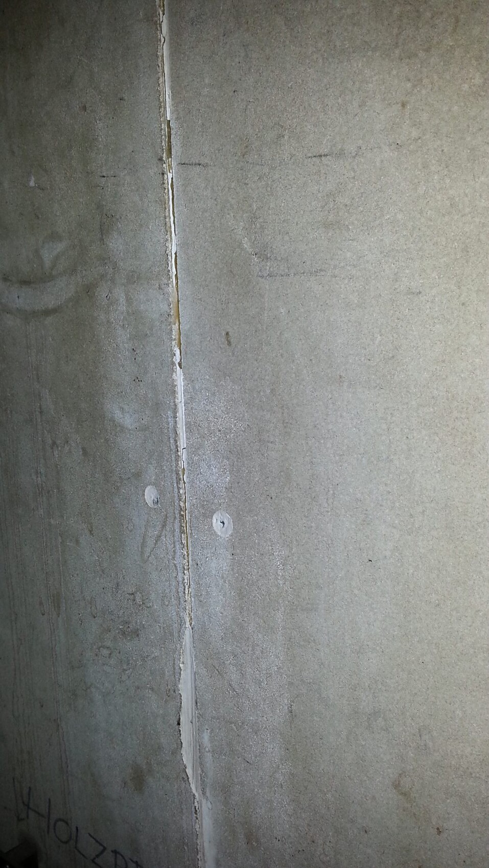 Unfinished concrete wall with joint and anchor bolts at the foundation area