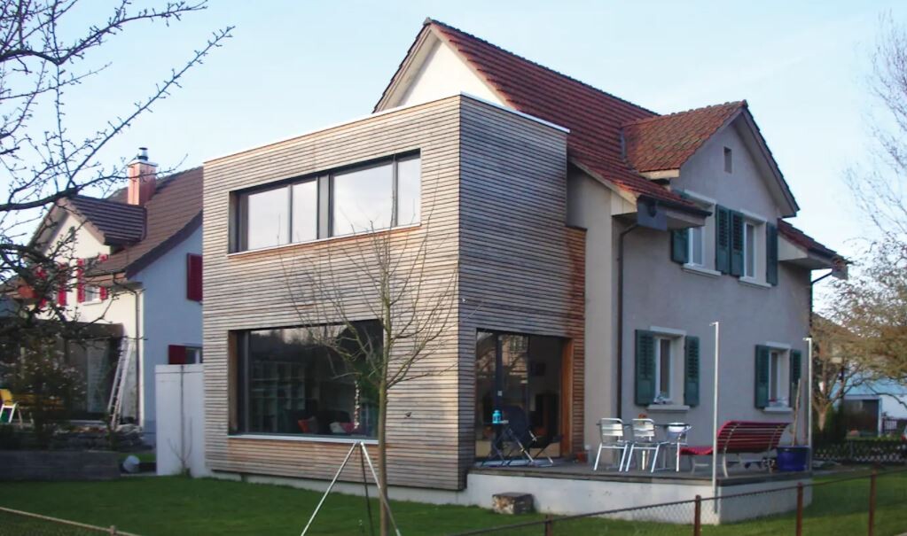 Modern two-story house with wooden cladding, terrace, and garden.