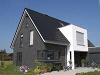 Modern house with dark brick facade and light-colored extension, exterior view.