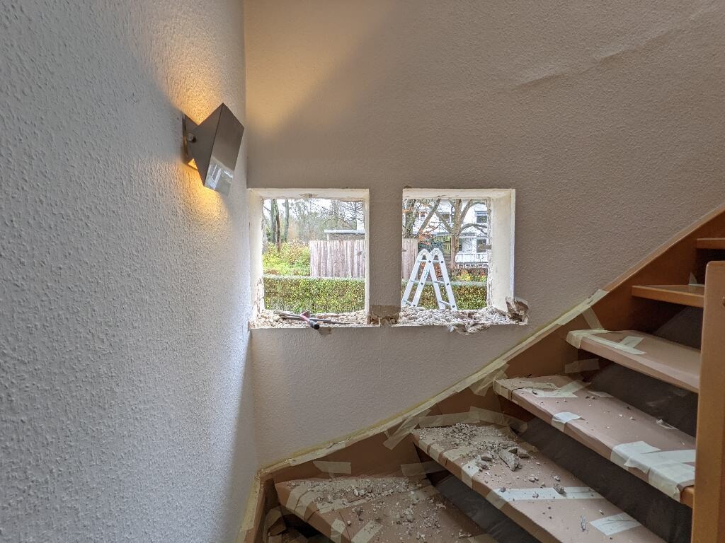Renovated stairwell with dust, two window openings, exterior ladder visible
