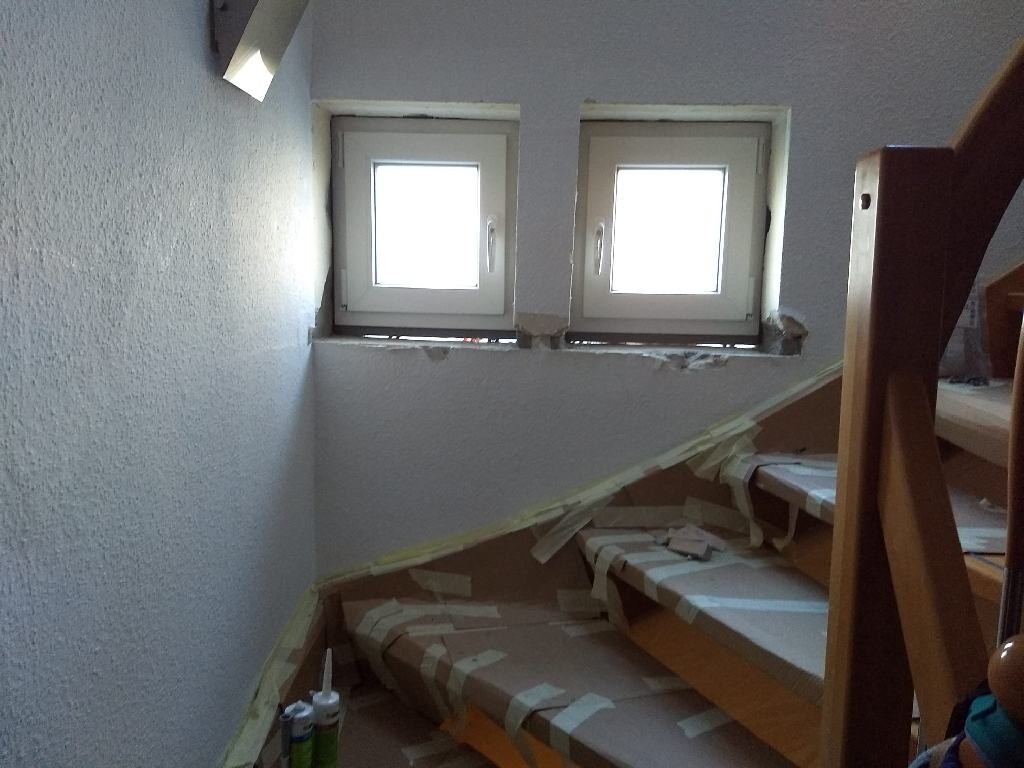 Attic room with two small windows; angled staircase, masking tape on the steps.