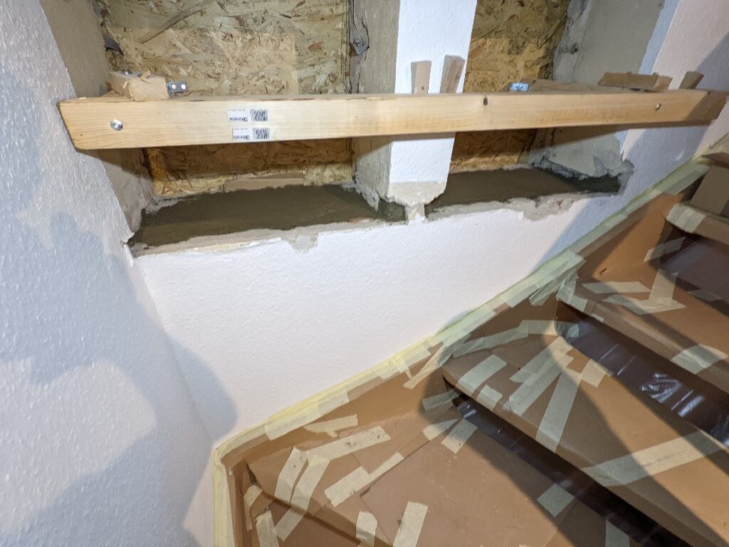 Construction site: wooden beam over styrofoam wall, OSB boards in the background, protective foil on the floor.