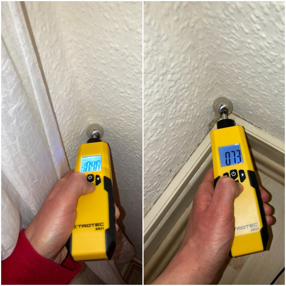 Yellow handheld device from Trotec at wall edge next to door frame for moisture measurement.