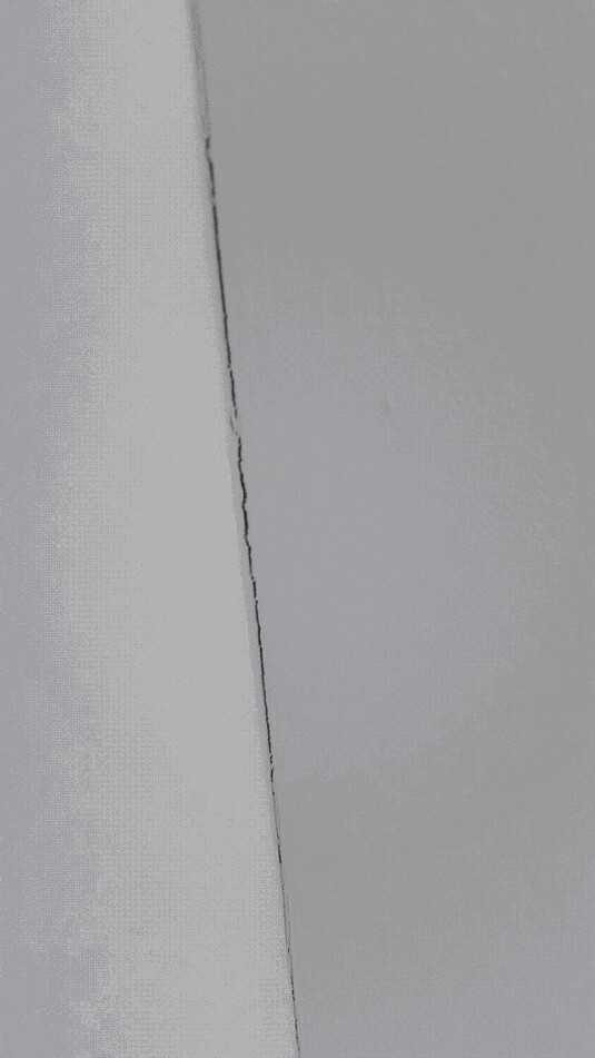 Close-up of an interior wall with a visible crack, indicating construction defects.