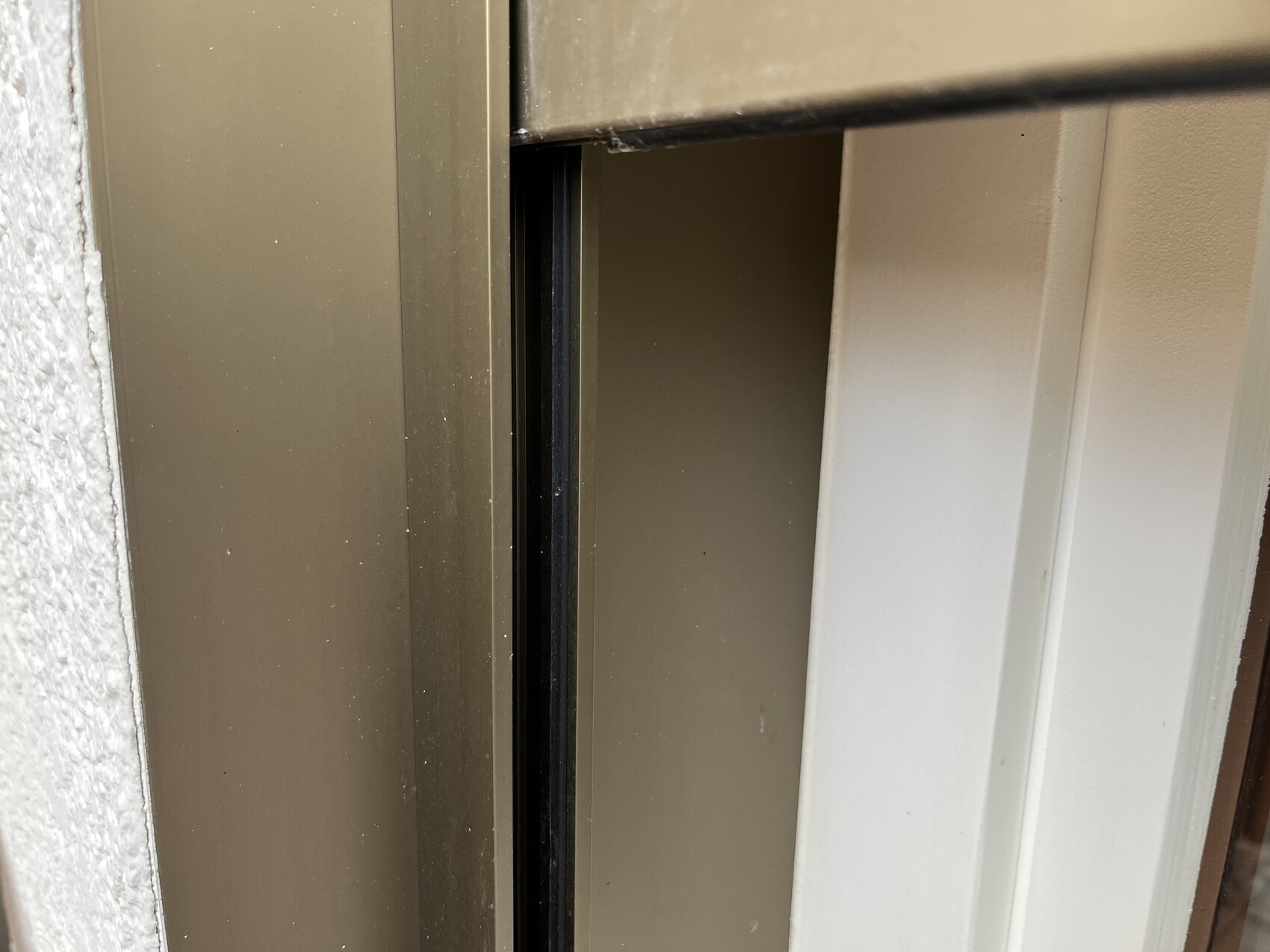 Close-up of a brown door/window frame with an open gap and dark interior