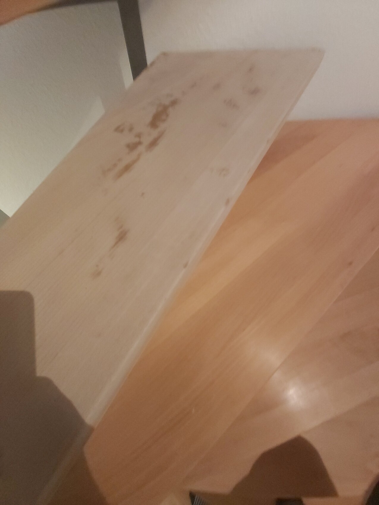 Von oben sichtbare helle Holztreppe mit geraden Stufen, Wand links.