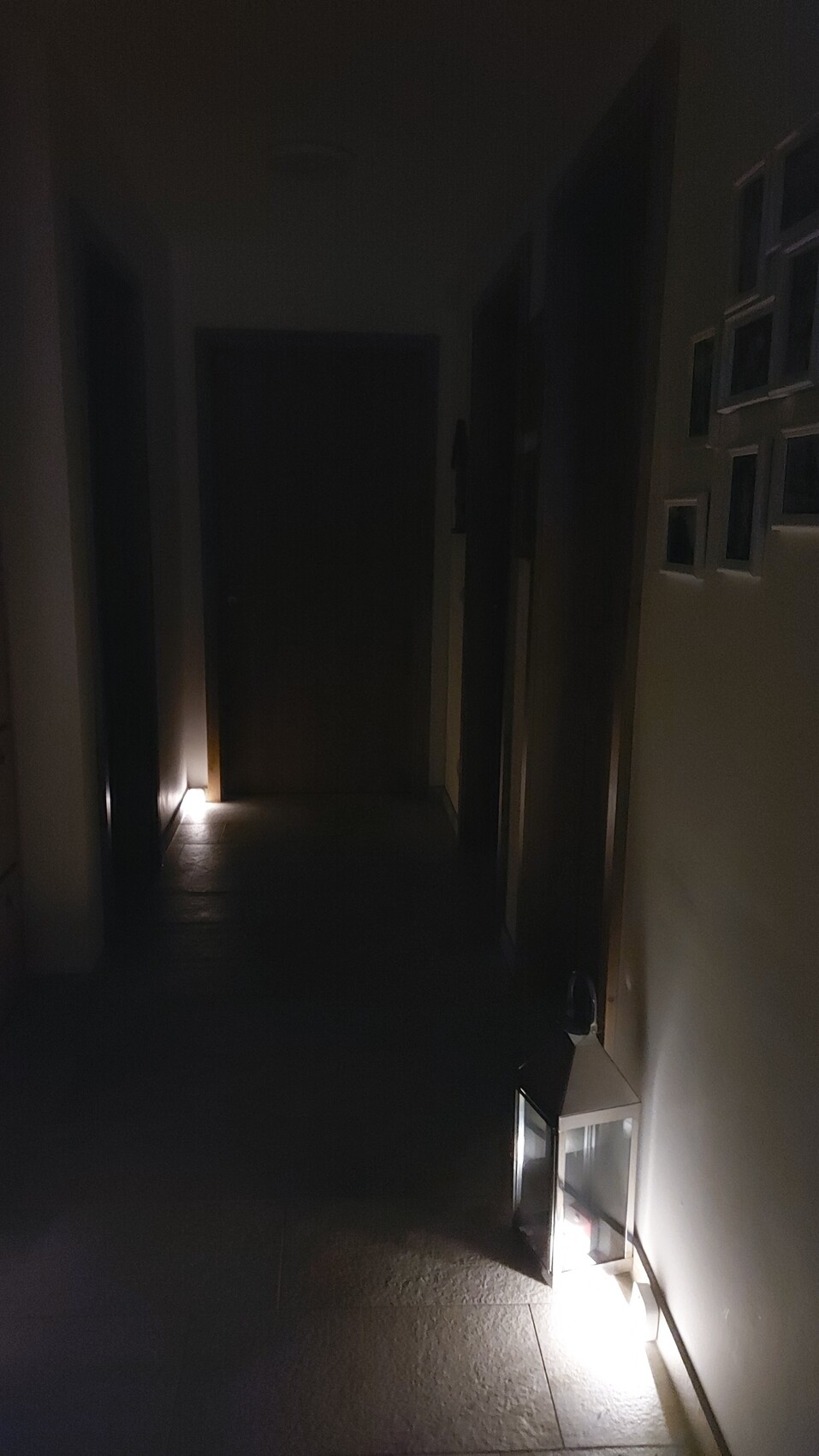 Dunkler Flur; rechts eine Laterne beleuchtet den Boden, Türen links und rechts.