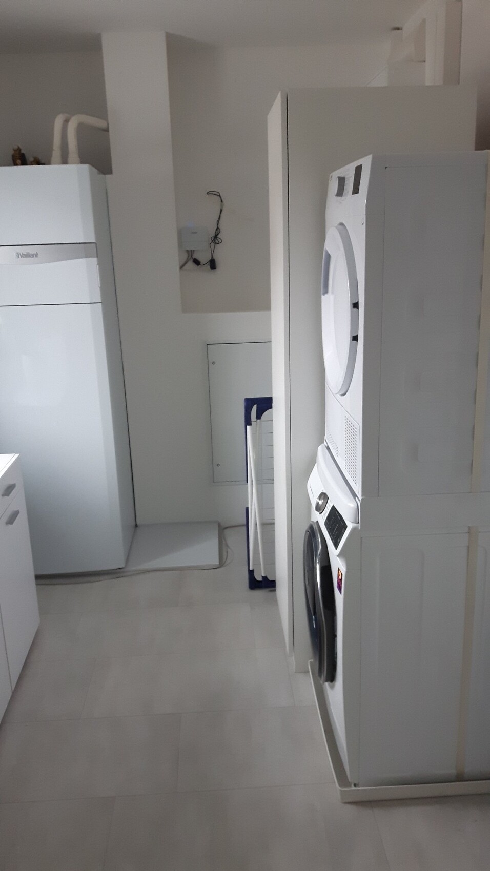 Laundry room with stacked washer and dryer, white cabinets.