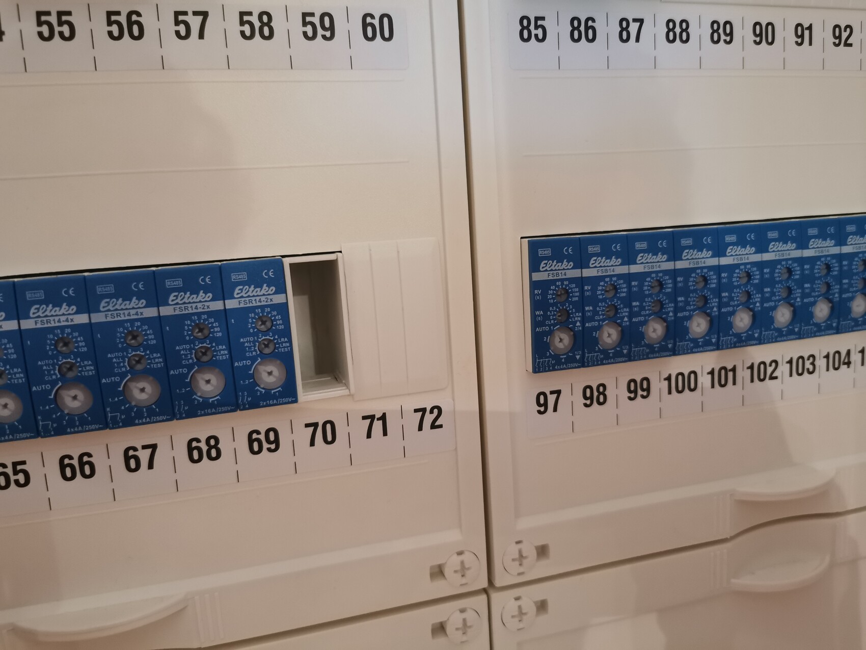 Distribution board with blue Eltako relay modules and numbered plug contacts.
