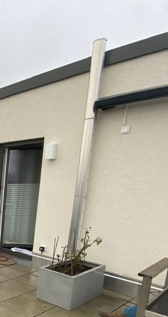 Exterior view of a terrace with vertical downpipe, planter, and window