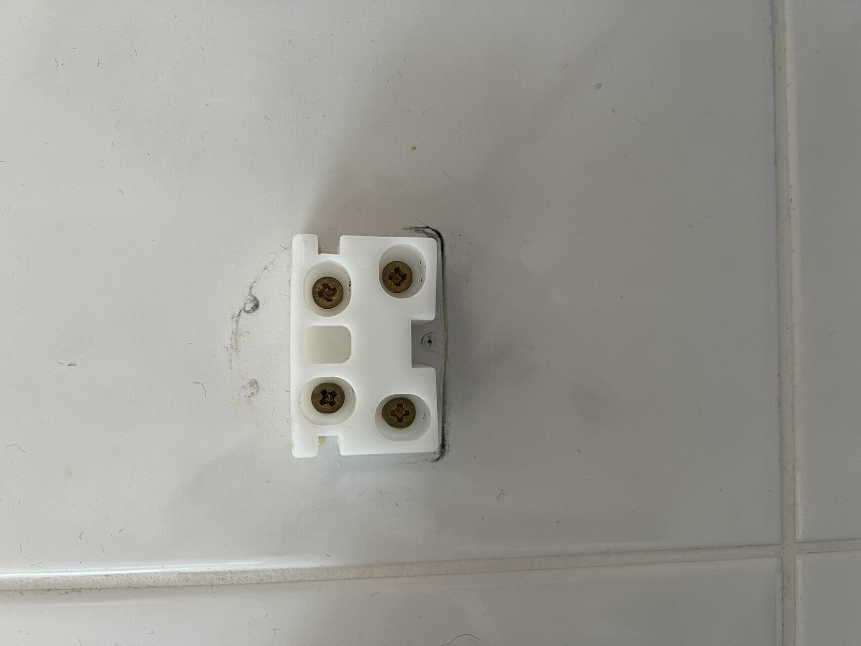 White terminal block with four screws on tiled wall