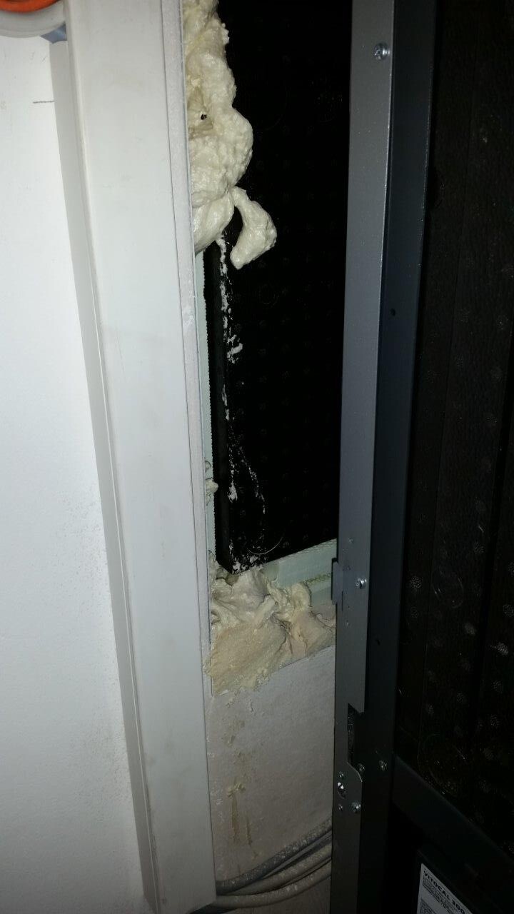 Close-up of a door frame with white insulating foam around the gap