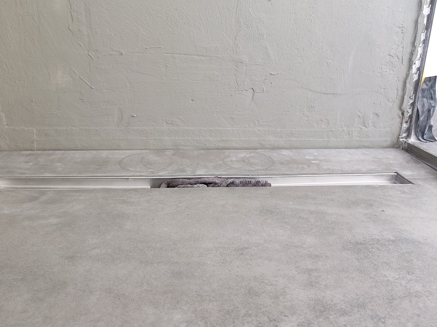 Shell construction: concrete floor with long metal channel; a cloth lies inside.