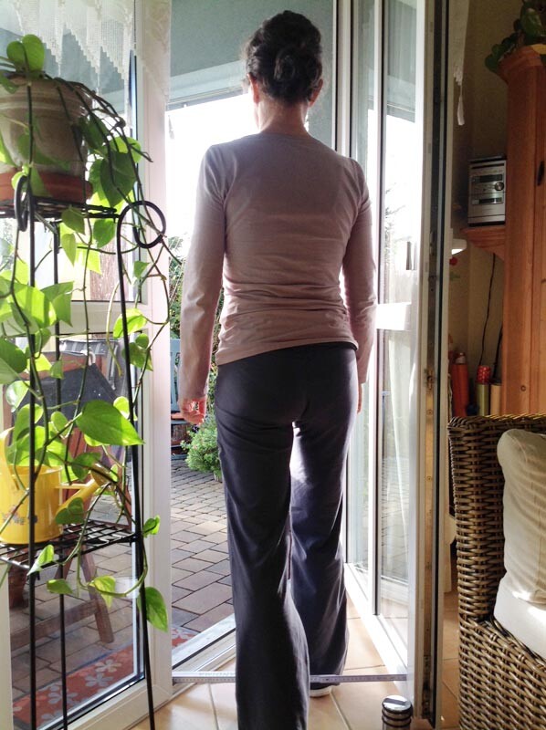 Rear view of a person in the entrance area in front of an open glass door to the garden