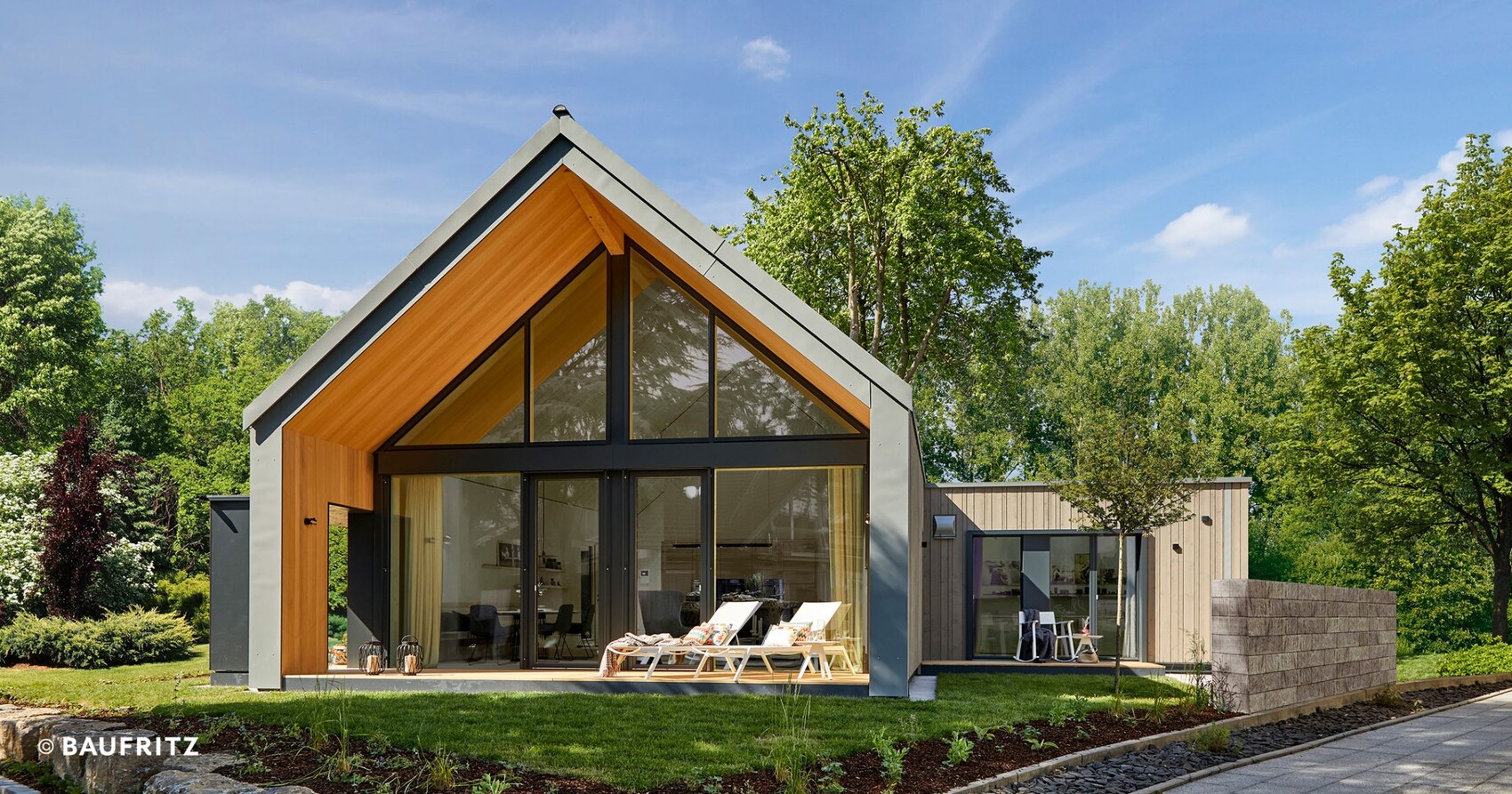 Modern house with large glass facade, wooden cladding, and green garden