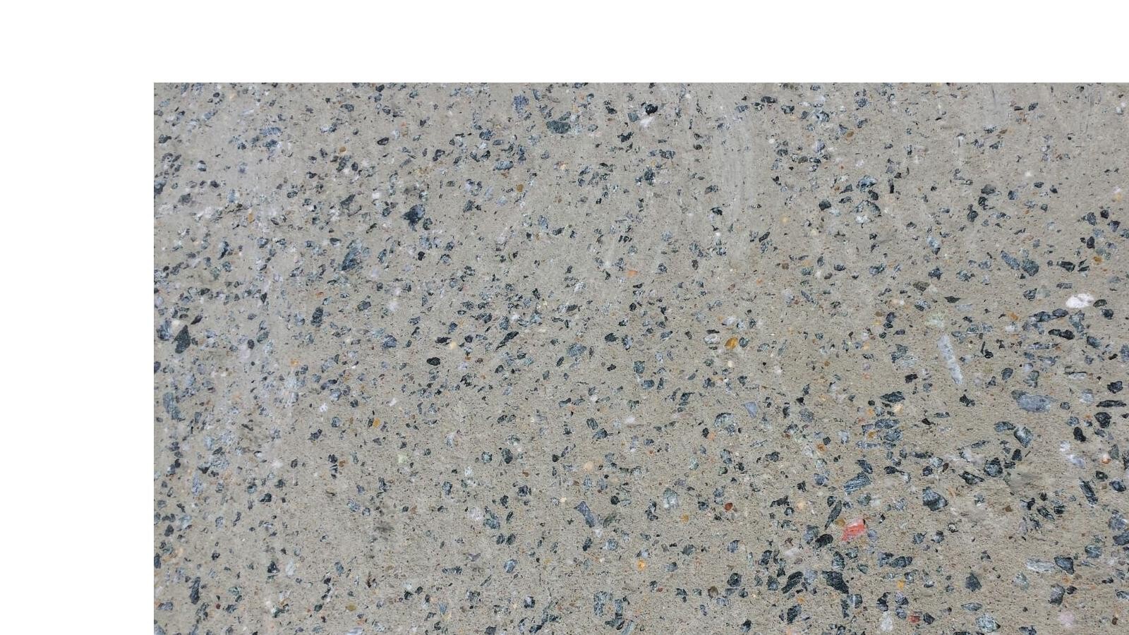 Exposed concrete floor with mixed gravel and small stones, roughly textured