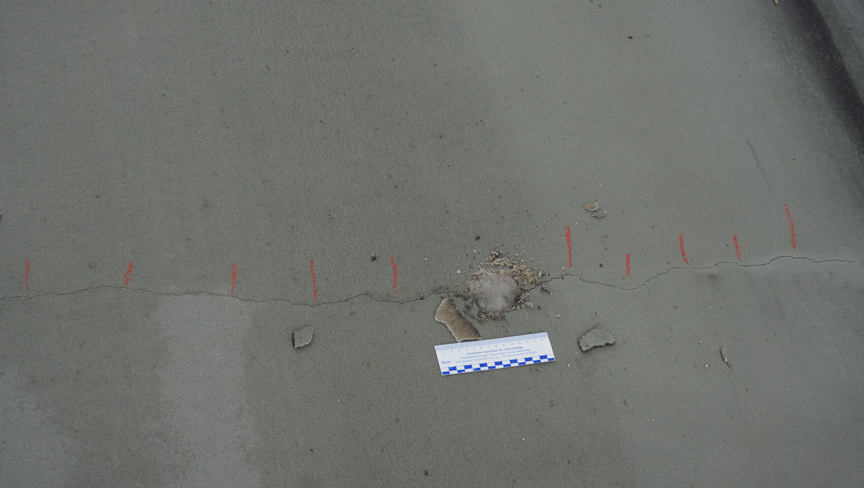 Concrete slab with visible crack, measuring scale and construction debris