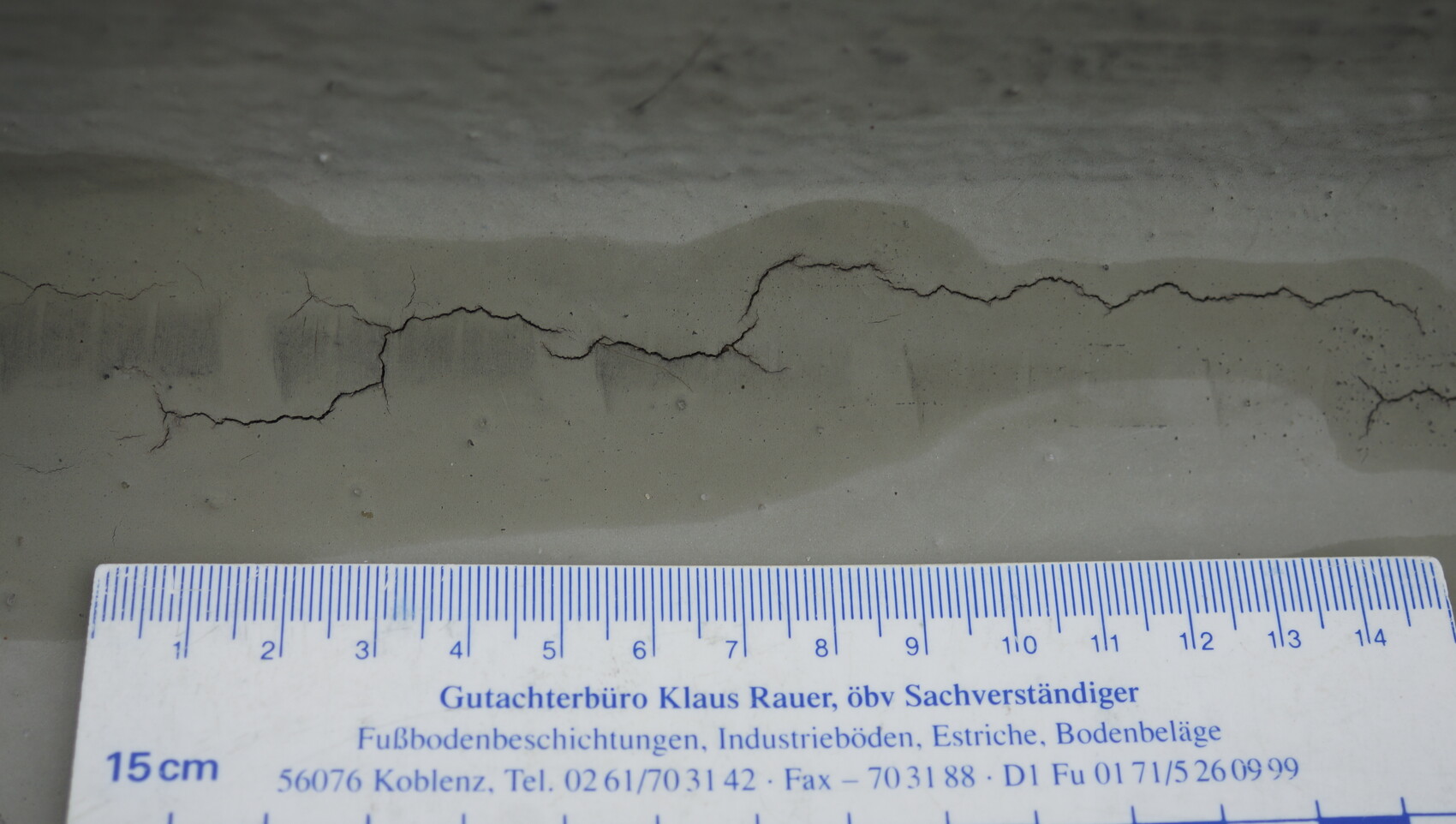 Concrete floor with cracks and measuring tape for documenting construction defects