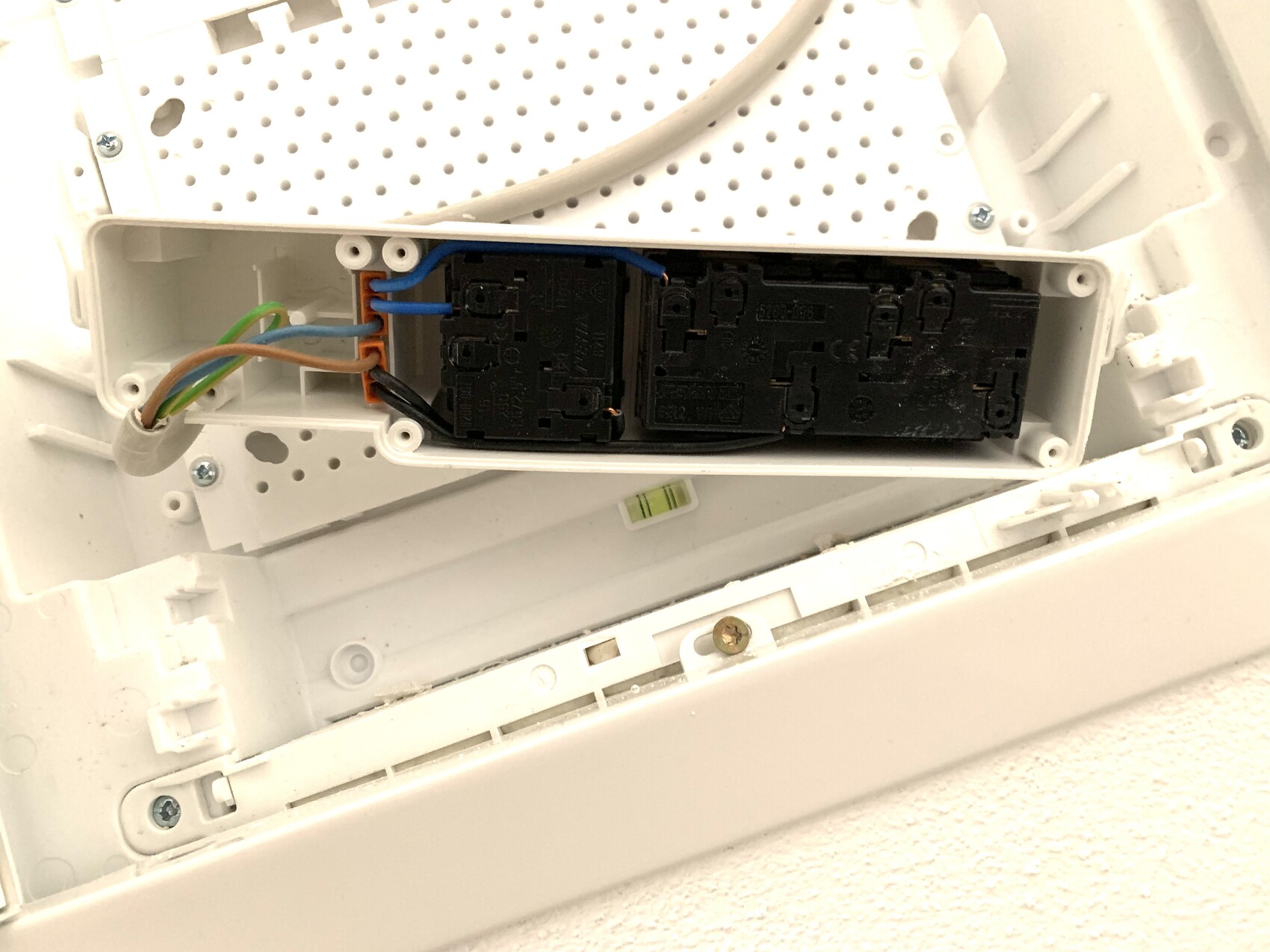Open white electronics enclosure with two black modules and colorful cables.