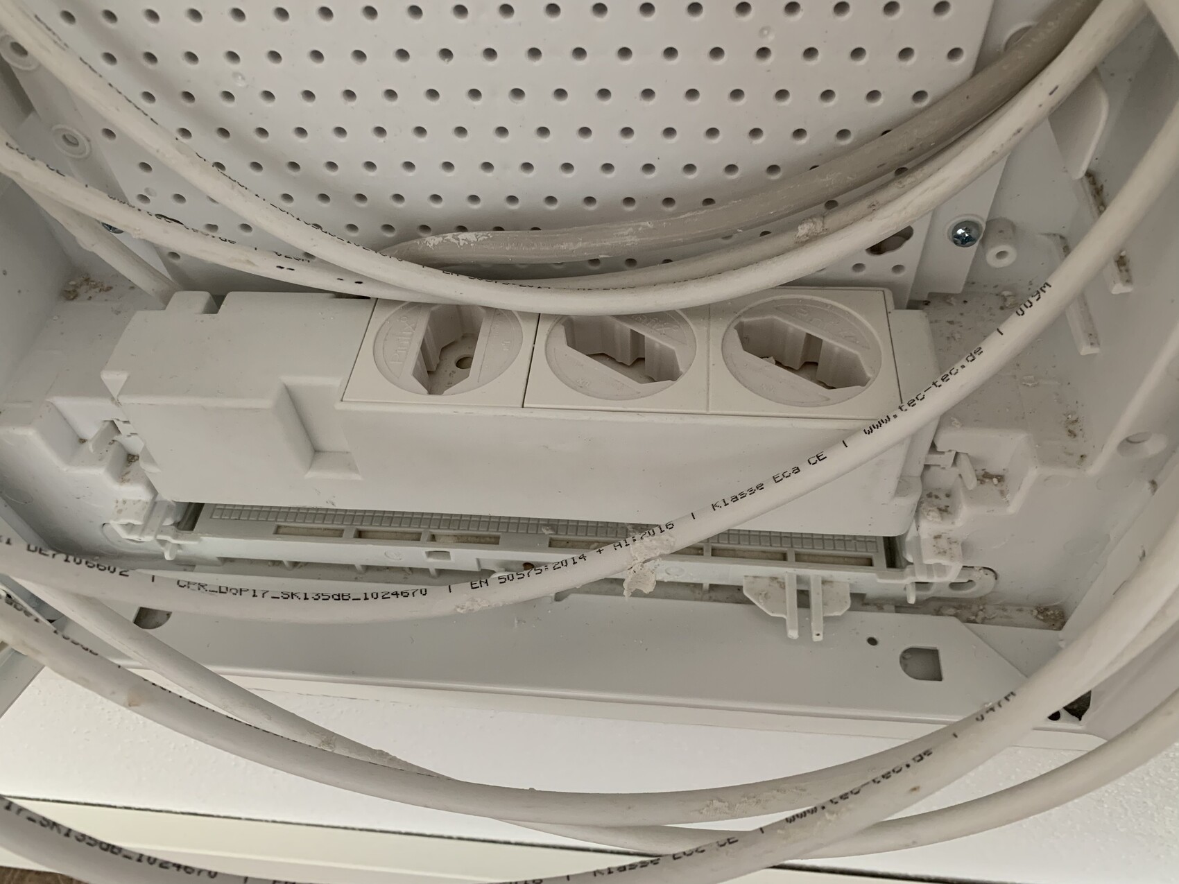 Close-up of a white power strip with three round Schuko sockets and cables.