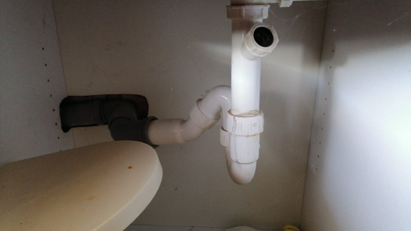 White PVC siphon with P-trap and drain connection visible under the sink
