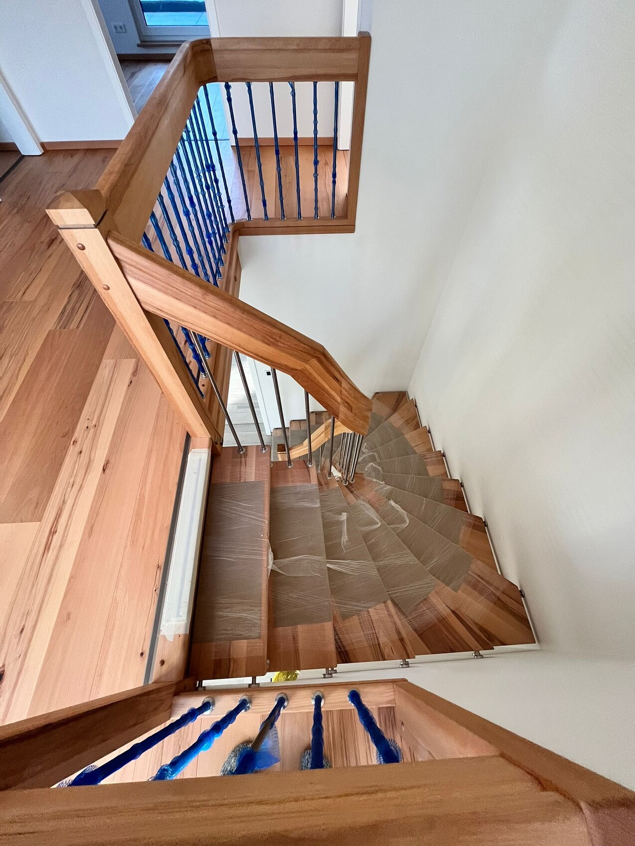Interior view of a multi-level wooden staircase with blue balusters and wooden handrail.