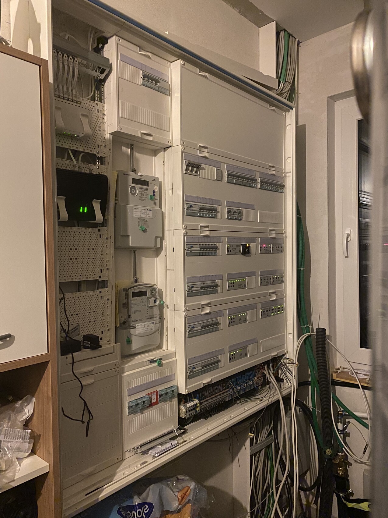 Electrical cabinet with DIN rail modules, several devices and LEDs; numerous cables visible.