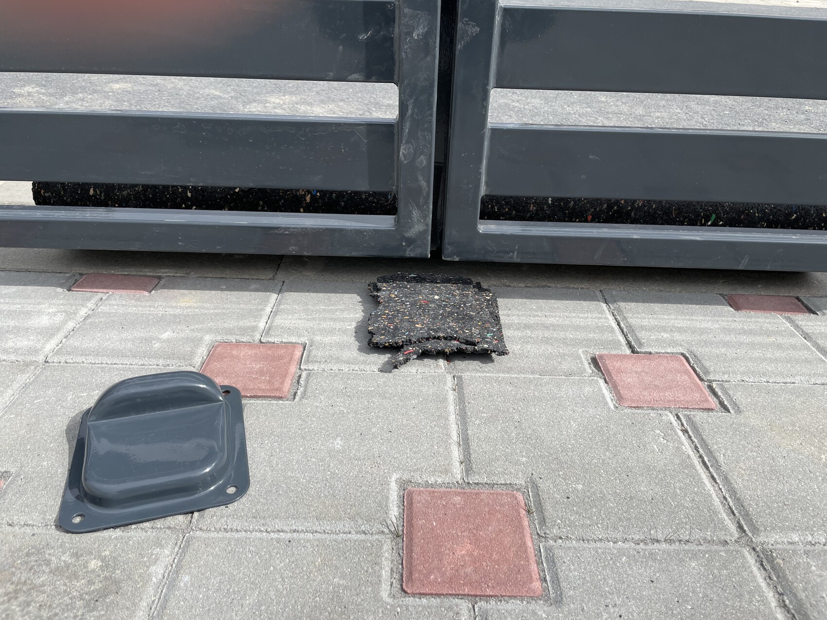 Gray metal gate, damaged paving slab on paved forecourt