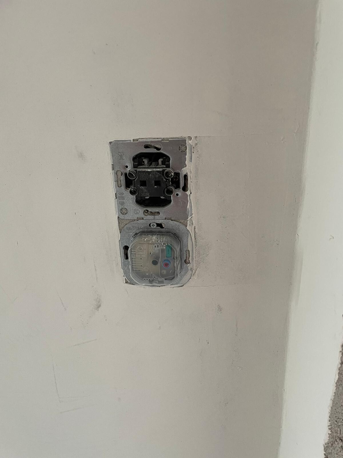 Open flush-mounted socket installation box with visible internal mechanics, cover missing.