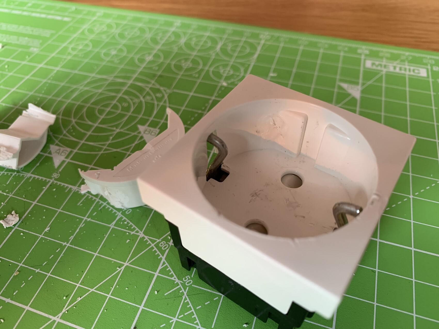 White round flush-mounted socket frame with metal contacts on green cutting mat