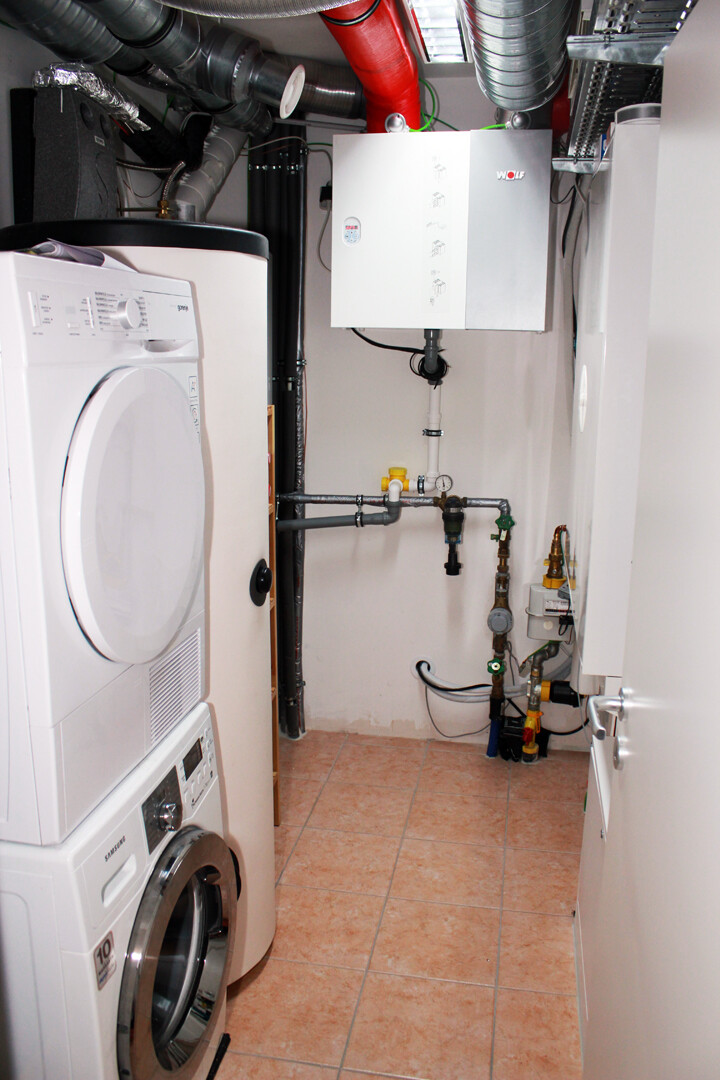Laundry/Utility room: Washing machine on the left, white heating system and pipework