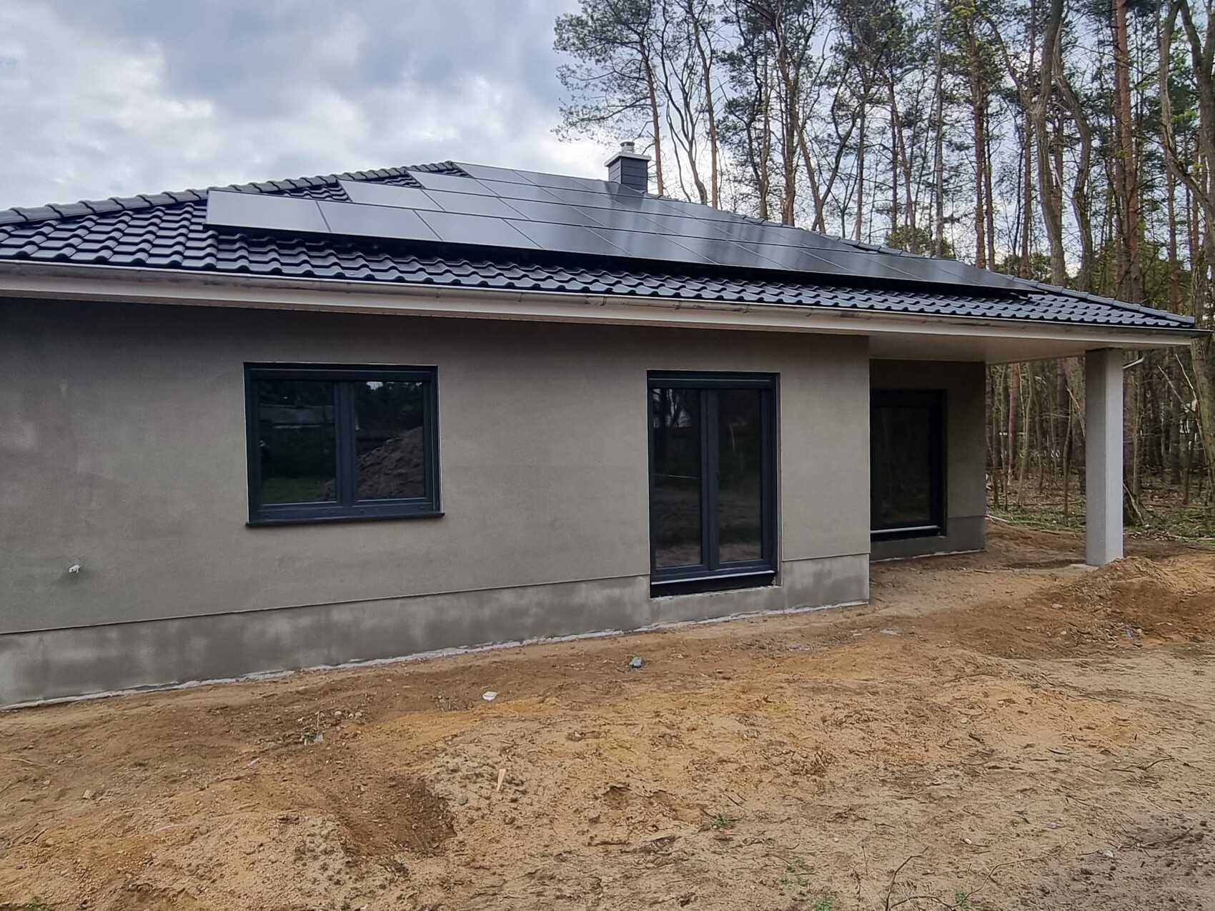 Modern single-family house with solar modules on the roof, gray facade and window front.