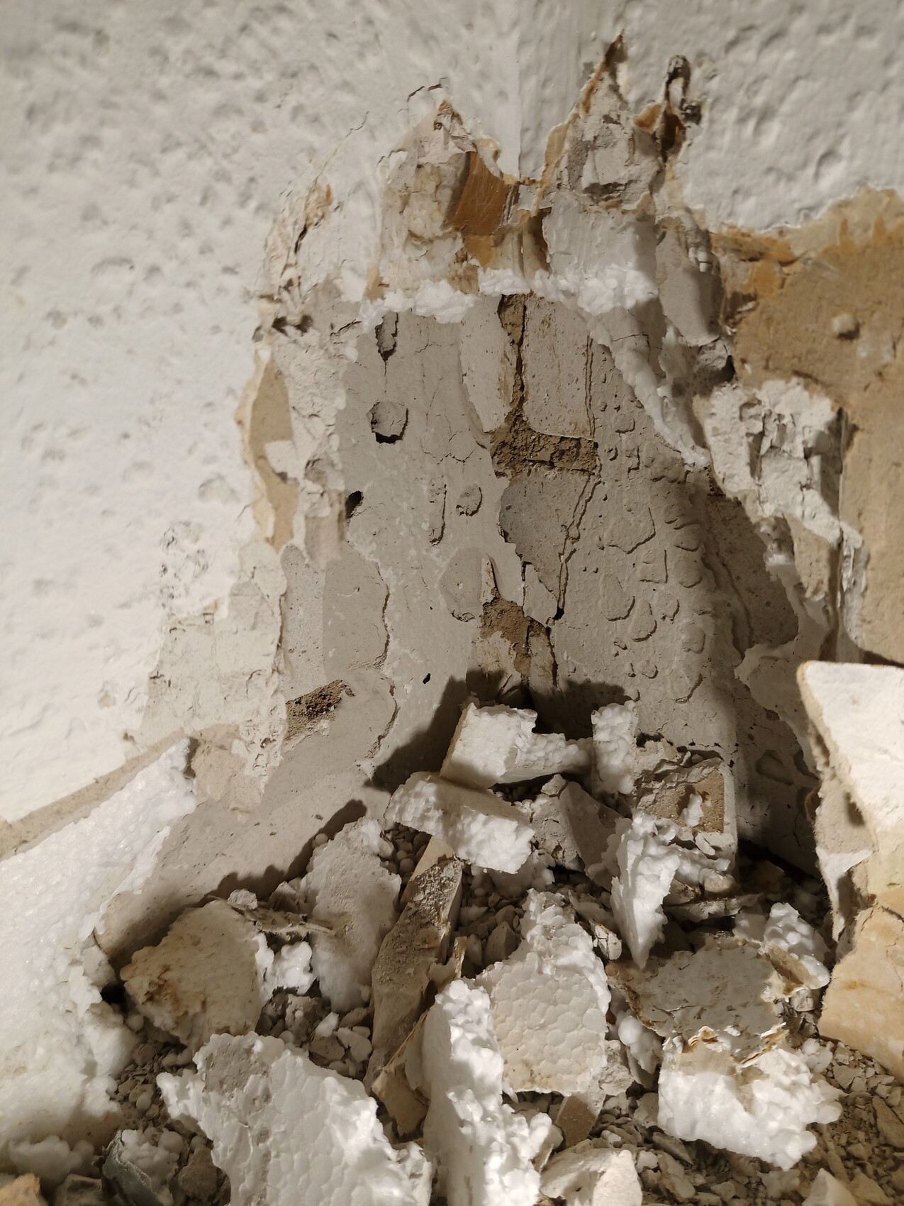 Damaged interior wall with crumbling plaster and debris