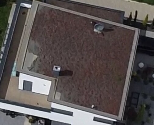 Aerial view of a brown flat roof with a small extension and satellite dish.