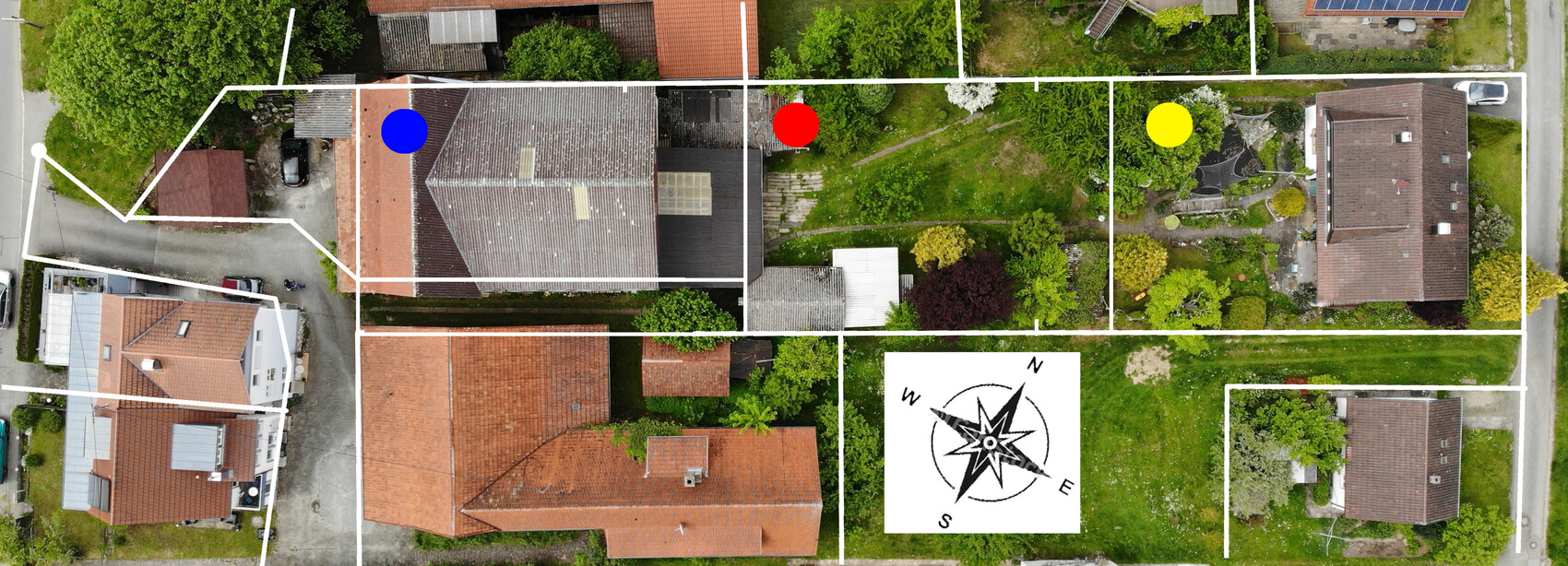 Aerial view of a residential area with white boundary lines, three colored dots (blue, red, yellow) and a compass rose.