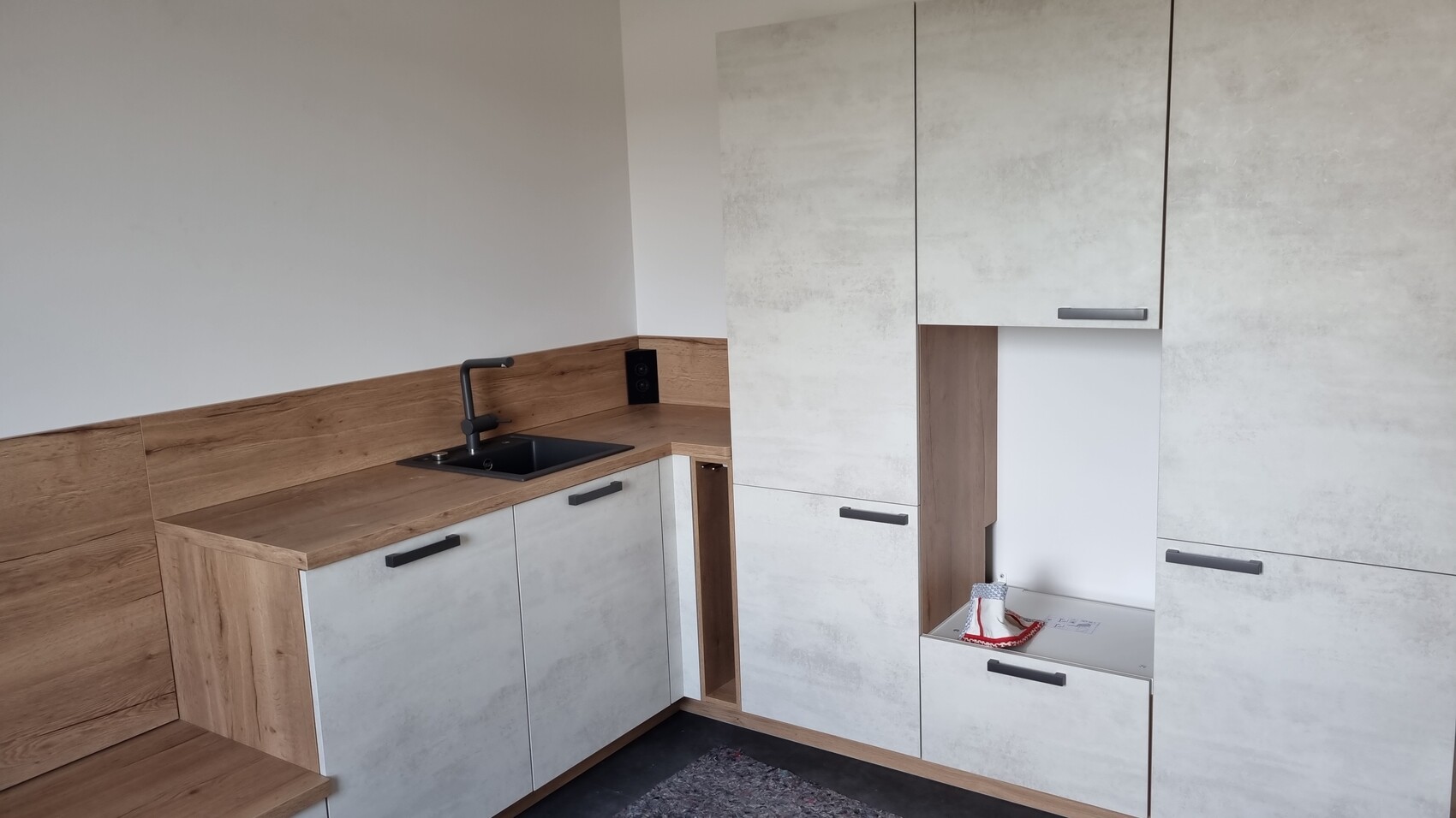 Modern kitchen with wooden worktop, gray fronts, black faucet and sink.